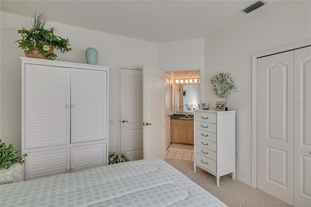 carpeted bedroom with connected bathroom and multiple closets