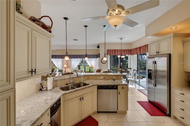 kitchen with stainless steel appliances, ceiling fan, sink, cream cabinets, and pendant lighting