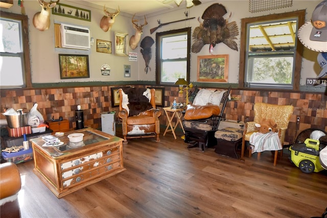 sitting room with plenty of natural light, an AC wall unit, and wood-type flooring