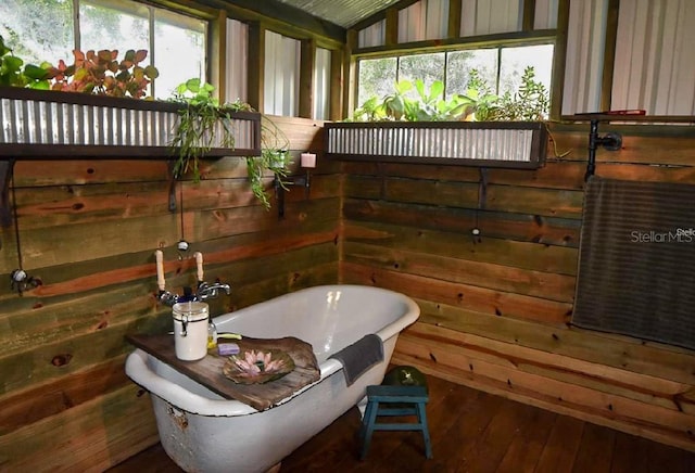 bathroom featuring vaulted ceiling, wood-type flooring, a washtub, and a wealth of natural light