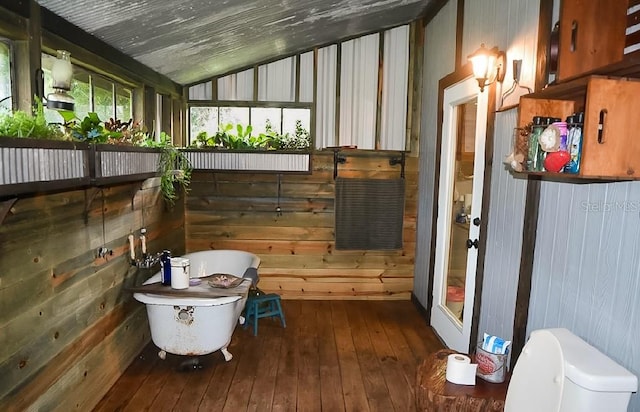 interior space with wood walls, hardwood / wood-style floors, and lofted ceiling