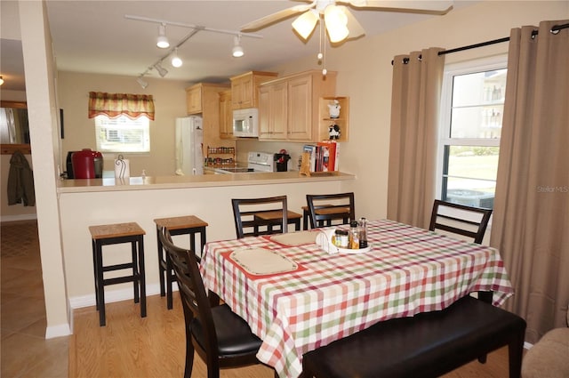 tiled dining room featuring rail lighting and ceiling fan