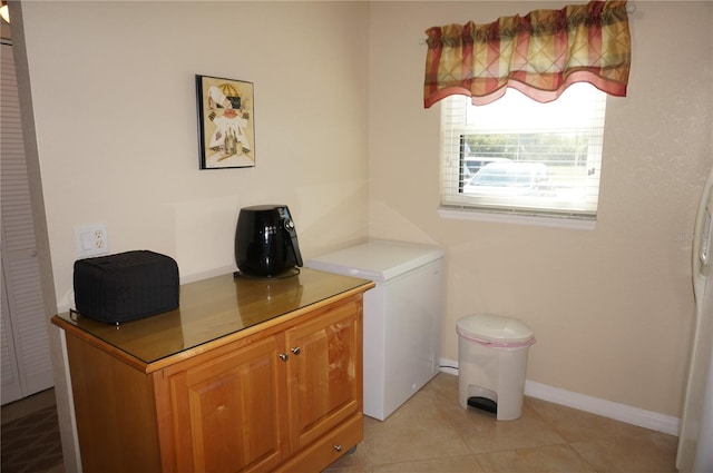 laundry room featuring light tile floors and cabinets