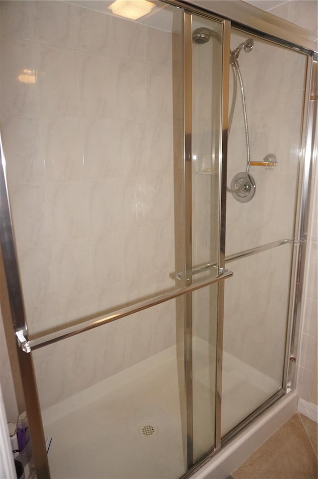 bathroom with a shower with shower door and tile flooring