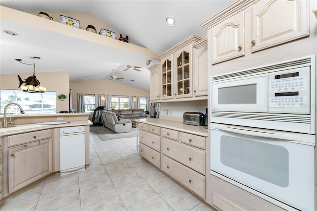 kitchen featuring lofted ceiling, white appliances, ceiling fan with notable chandelier, hanging light fixtures, and sink