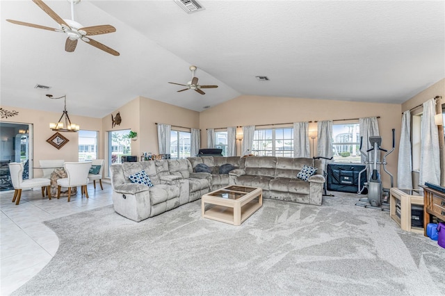 living room with ceiling fan with notable chandelier, light tile patterned floors, a textured ceiling, and vaulted ceiling