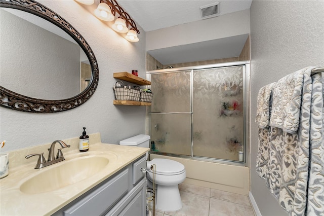 full bathroom with a textured ceiling, vanity, shower / bath combination with glass door, tile patterned flooring, and toilet