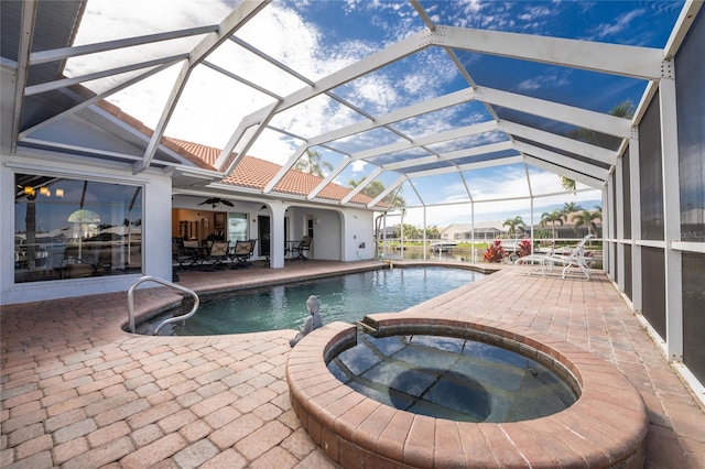 view of swimming pool with glass enclosure, an in ground hot tub, ceiling fan, and a patio