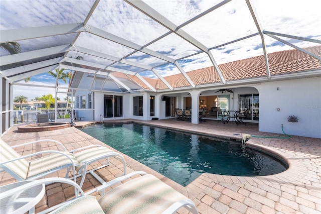 view of pool with glass enclosure, a patio area, ceiling fan, and an in ground hot tub