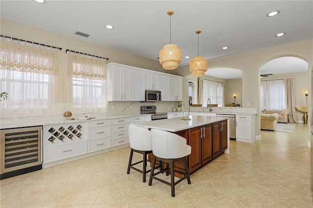 kitchen featuring beverage cooler, a center island, appliances with stainless steel finishes, and white cabinetry