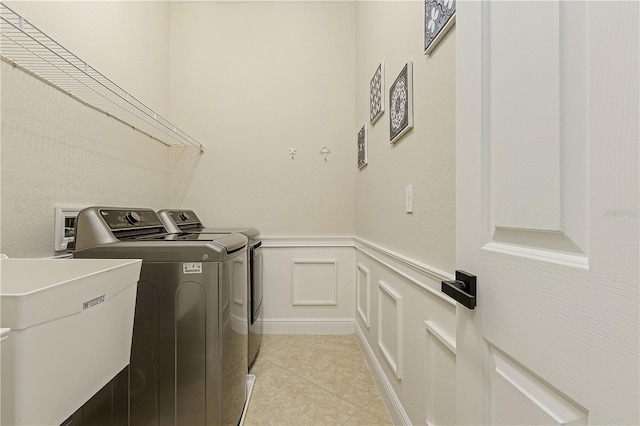 clothes washing area with light tile flooring, separate washer and dryer, and sink