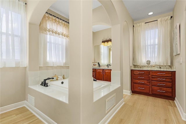 bathroom with plenty of natural light, hardwood / wood-style floors, a bathtub, and vanity