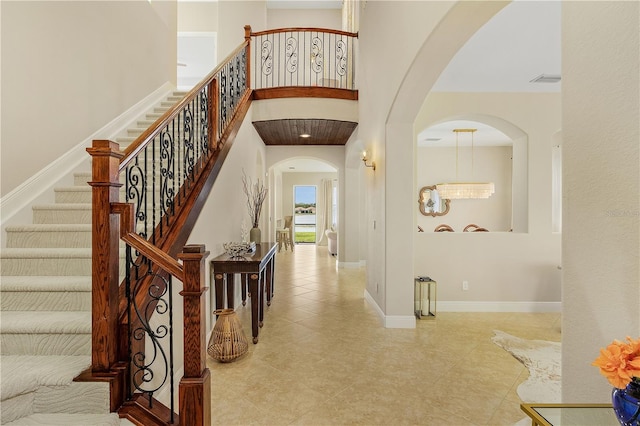 entrance foyer with light tile floors, a high ceiling, and an inviting chandelier