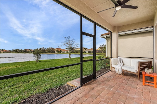 sunroom featuring ceiling fan and a water view