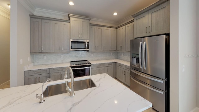 kitchen with light stone counters, backsplash, stainless steel appliances, and gray cabinetry