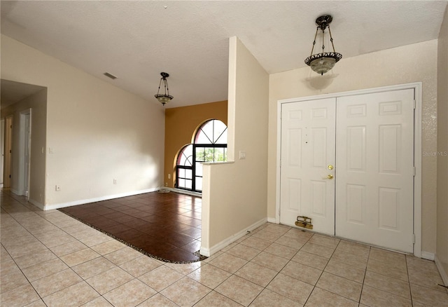 entryway with lofted ceiling, a textured ceiling, and light tile patterned floors