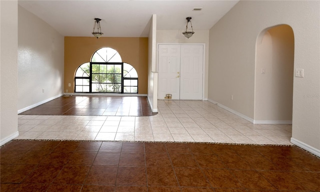 tiled spare room featuring vaulted ceiling