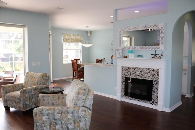 living room with a tiled fireplace and dark hardwood / wood-style flooring