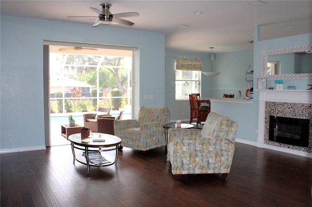 living room featuring ceiling fan, a tile fireplace, and dark hardwood / wood-style flooring