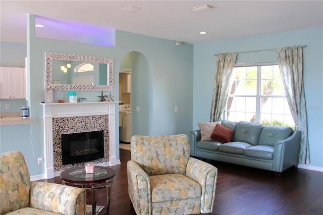 living room featuring dark wood-type flooring, washer / dryer, and a tile fireplace