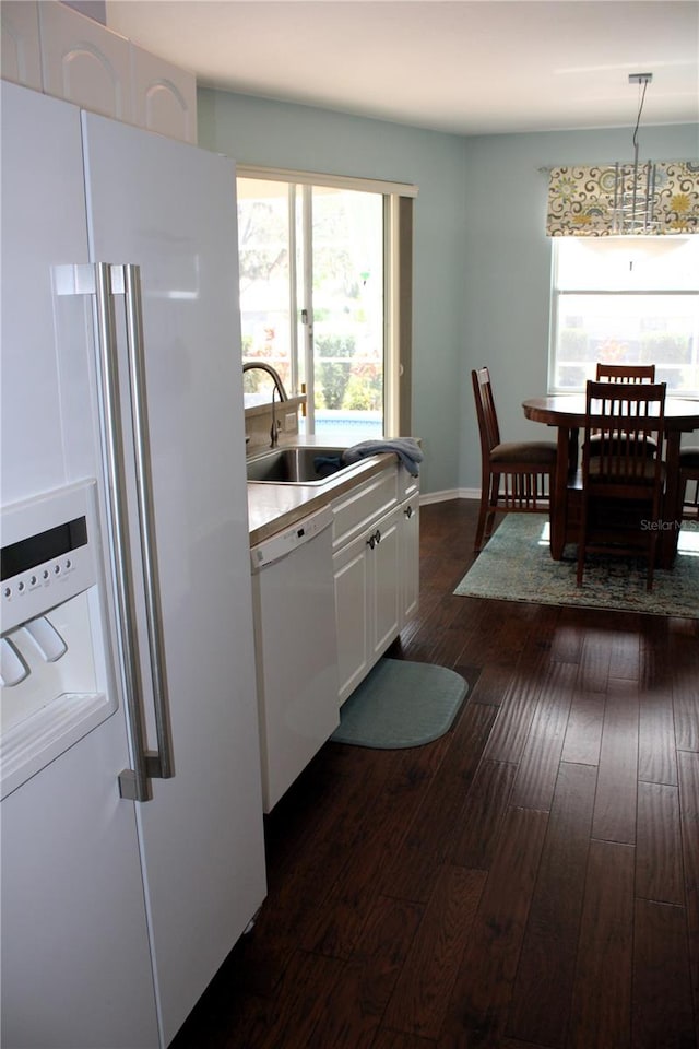 kitchen with dark hardwood / wood-style floors, hanging light fixtures, sink, white cabinetry, and white appliances