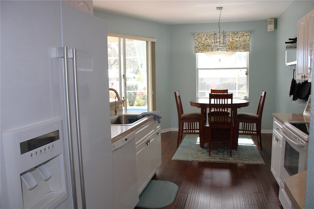 kitchen featuring white appliances, sink, pendant lighting, white cabinets, and dark wood-type flooring