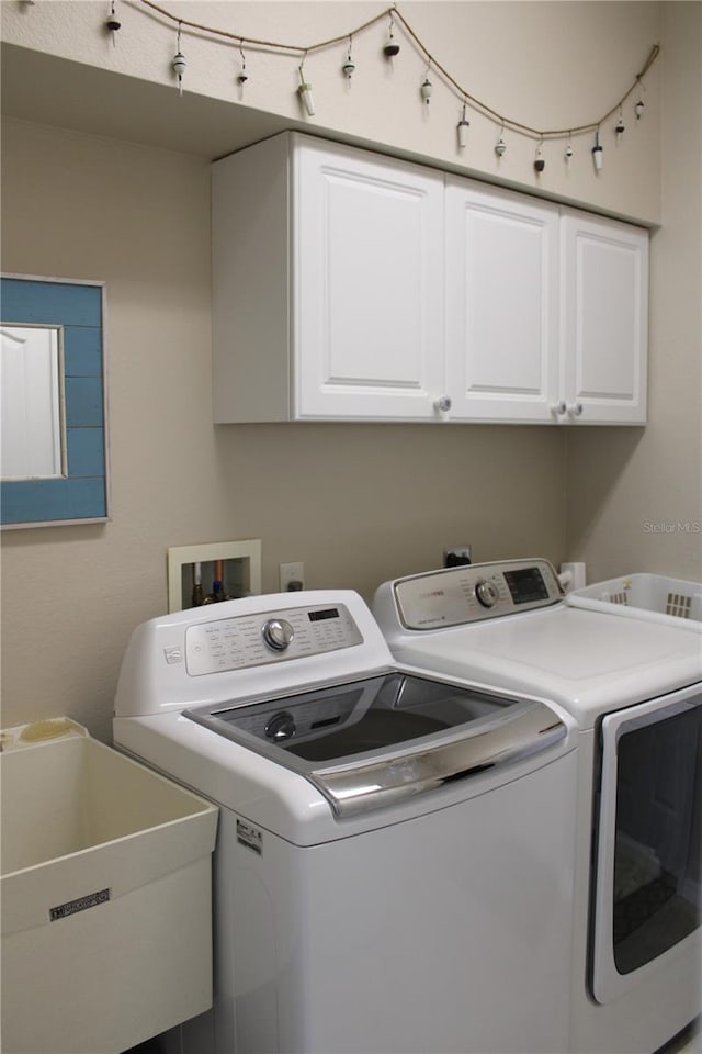 laundry room with sink, washer and dryer, and cabinets