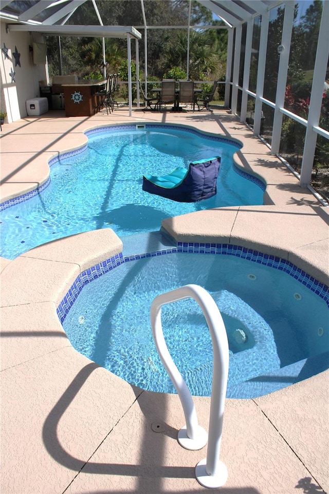 view of pool with a patio, an in ground hot tub, and glass enclosure