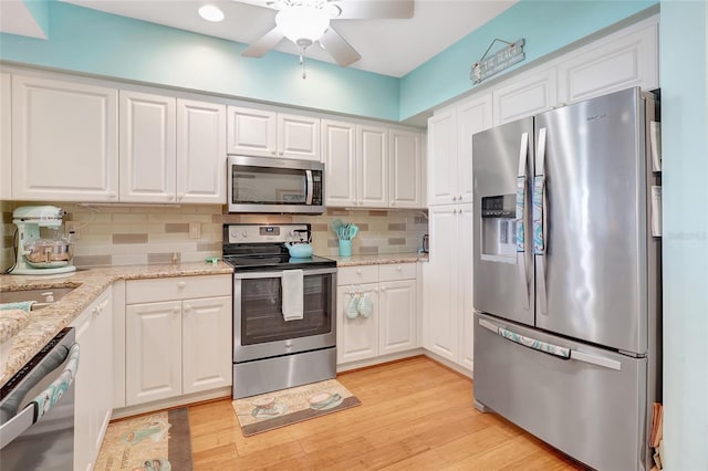 kitchen with appliances with stainless steel finishes, backsplash, light hardwood / wood-style floors, and white cabinets