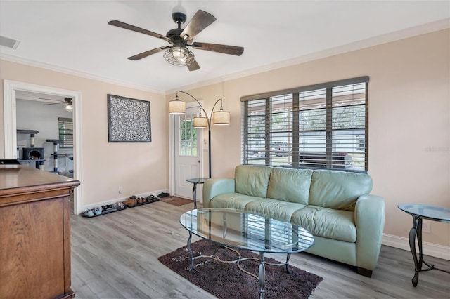 living room with light hardwood / wood-style floors, ceiling fan, and crown molding