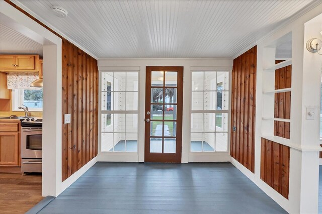 doorway with built in shelves, sink, dark hardwood / wood-style flooring, wood walls, and ornamental molding