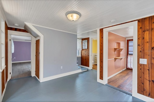 spare room featuring ornamental molding, wooden walls, and dark wood-type flooring