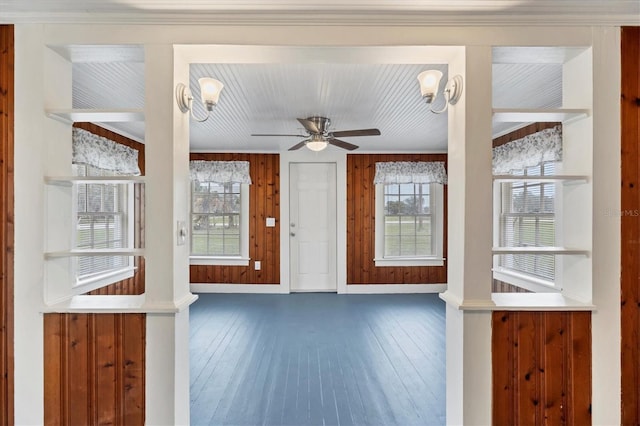 foyer entrance with ceiling fan, dark hardwood / wood-style flooring, and wood walls