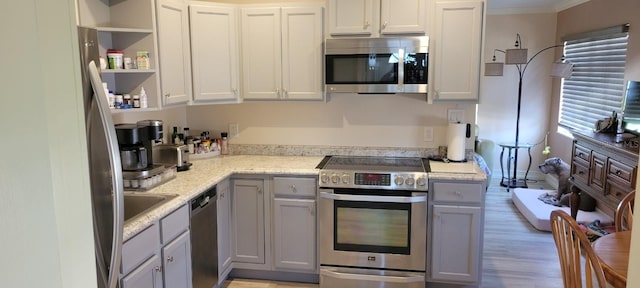 kitchen featuring gray cabinets, light stone countertops, ornamental molding, light hardwood / wood-style floors, and stainless steel appliances