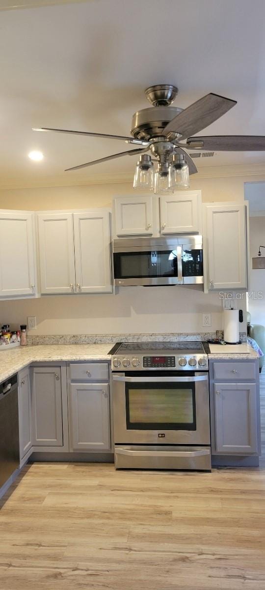 kitchen with gray cabinetry, white cabinets, stainless steel appliances, and light wood-type flooring