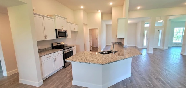 kitchen featuring stainless steel appliances, kitchen peninsula, sink, light stone countertops, and white cabinets