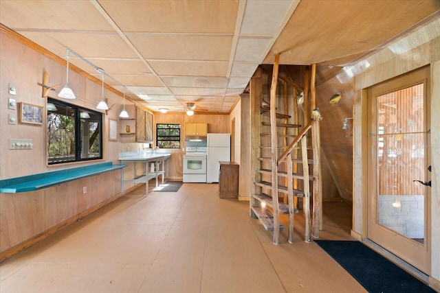 basement with wood walls, white fridge, and ceiling fan