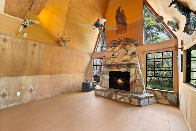 living room with ceiling fan, a stone fireplace, and high vaulted ceiling