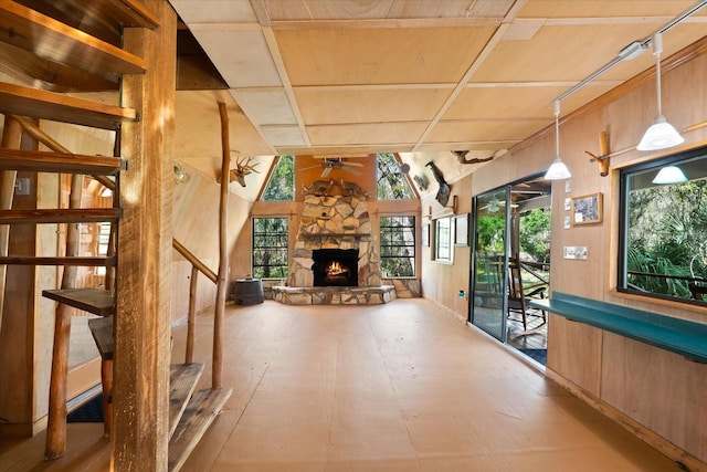 unfurnished living room featuring a fireplace, ceiling fan, wooden walls, and coffered ceiling