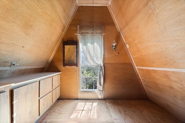 bonus room featuring light wood-type flooring and wooden walls