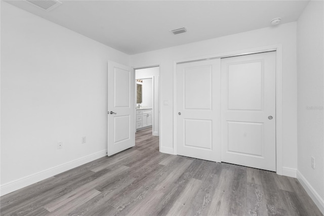 unfurnished bedroom featuring a closet, baseboards, visible vents, and light wood finished floors