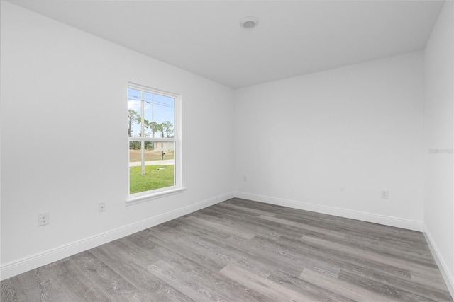 spare room featuring baseboards and wood finished floors