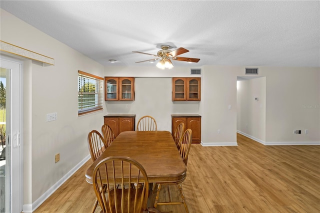 dining area with light hardwood / wood-style floors, a textured ceiling, and ceiling fan