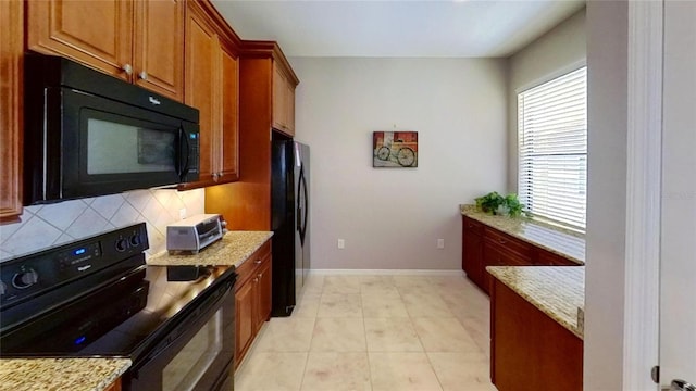 kitchen with backsplash, light stone counters, light tile flooring, and black appliances