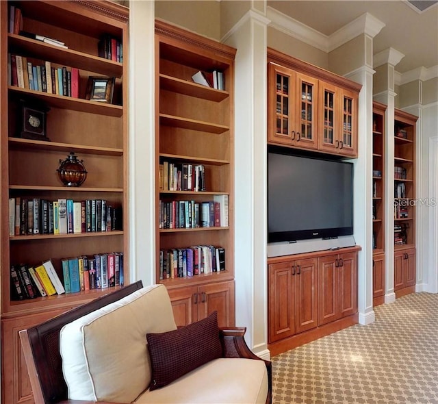 sitting room with light colored carpet, crown molding, and built in shelves