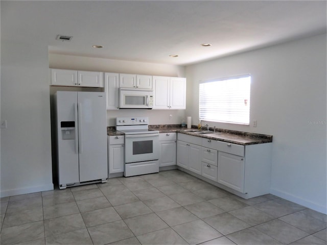 kitchen featuring white appliances, white cabinets, sink, and light tile floors