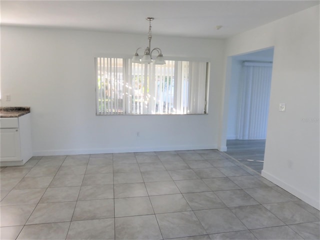 unfurnished dining area with a notable chandelier and light tile floors