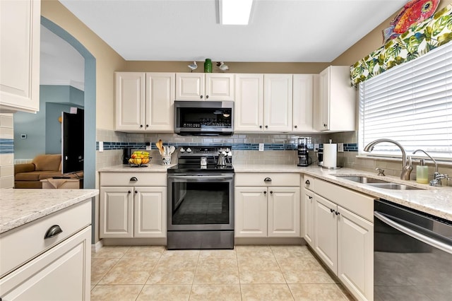 kitchen with backsplash, appliances with stainless steel finishes, sink, light tile floors, and white cabinets