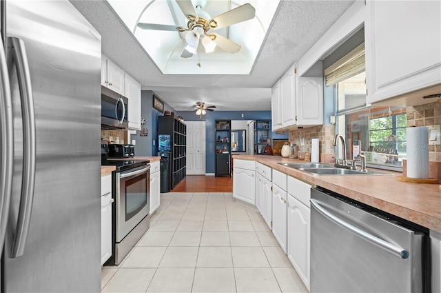 kitchen with a textured ceiling, appliances with stainless steel finishes, decorative backsplash, and white cabinets