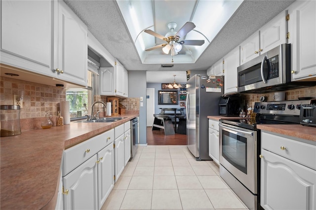 kitchen featuring stainless steel appliances, white cabinets, light tile patterned floors, and a textured ceiling